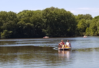 Familie sejler på søen ved Luxe Camping Borken am See - Glamping Noordrijn-Westfalen omgivet af grønne træer.