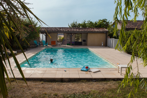 Piscina all'aperto a Nature's Pace Holidays - Glamping Occitanie, contornata da terrazza, sedie e verde.