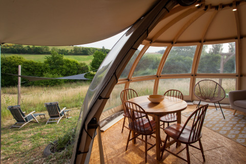 Vue intérieure d'une tente glamping chez Nature's Pace Holidays - Glamping Occitanie avec mobilier en bois.