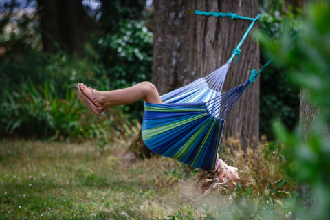 Un enfant joue dans un hamac coloré chez Nature's Pace Holidays - Glamping Occitanie, en pleine nature.