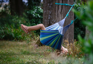 Et barn leger i en hængekøje mellem træerne hos Nature's Pace Holidays - Glamping Occitanie, omgivet af natur.