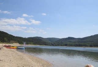 Strand ved sø med kanoer og kajakker, bakket landskab og glamping i Occitanie, Nature's Pace Holidays.