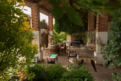 Espace détente couvert chez Nature's Pace Holidays - Glamping Occitanie, avec jeux et plante luxuriante.
