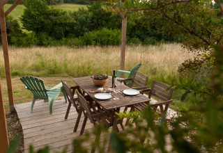 Zona pranzo esterna con tavolo e sedie in legno da Nature's Pace Holidays - Glamping Occitanie nella natura.