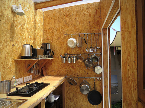 Rustieke glamping keuken met houten muren, fornuis, pannen en keukengerei bij Nature's Pace Holidays Occitanie.