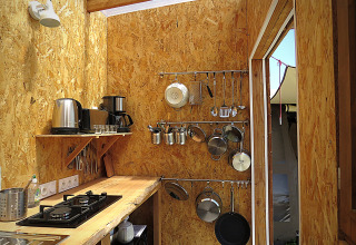 Cucina rustica da glamping con pareti in legno, utensili e pentole da Nature's Pace Holidays Occitanie.