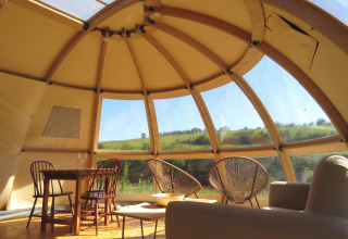 Vue intérieure d’un dôme de glamping Nature’s Pace Holidays avec mobilier et belle vue sur la campagne.