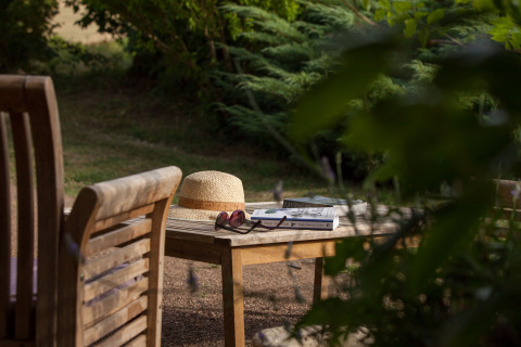 Area glamping di Nature's Pace Holidays - Glamping Occitanie, con cappello, libri e occhiali su tavolo di legno.