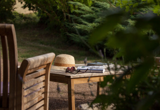 Naturferien bei Nature's Pace Holidays - Glamping Occitanie mit Holzmöbeln, Büchern, Sonnenbrille und Strohhut.