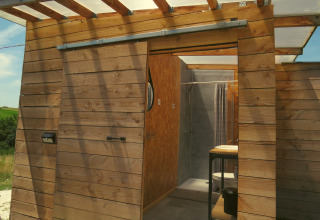 Cabane de glamping extérieure en bois avec porte coulissante, vue sur salle de bain moderne, Nature's Pace Holidays.