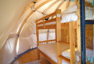 Interior of a glamping tent with wooden bunk beds at Nature's Pace Holidays - Glamping Occitanie, France.