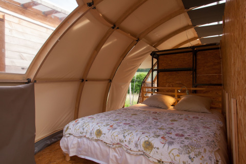 Glamping accommodation at Nature's Pace Holidays in Occitanie featuring a cozy double bed in a tent cabin.
