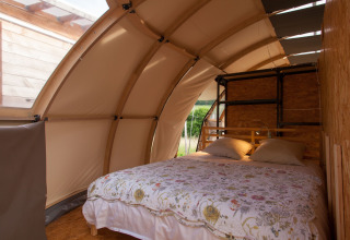Alojamiento glamping en Nature's Pace Holidays, Occitania, con cama doble en cabaña estilo tienda.