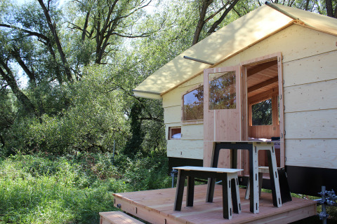 Glamping accommodation in nature featuring a modern wooden cabin and outdoor seating at Werkhaus Destinature.