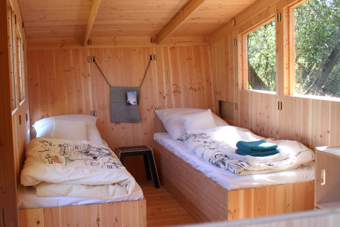 Vista interior de la WERKHAUS destinature Basic lodge con dos camas individuales de madera en Baja Sajonia.