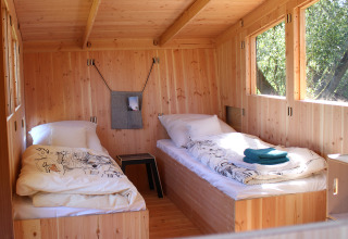 Vue intérieure de la WERKHAUS destinature Basic lodge avec deux lits simples en bois en Basse-Saxe.