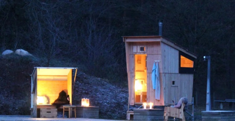 Glampingindkvartering hos WERKHAUS destinature - Basic lodge i Nedersaksen, med oplyste træhytter om aftenen.