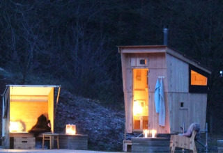 Alojamiento glamping en WERKHAUS destinature - Basic lodge en Baja Sajonia, con cabañas de madera iluminadas de noche.