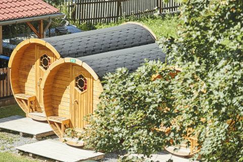 Træhytter formet som vintønder på Camping Dreiländereck - Lodge & Wijnvat Tirol, omgivet af natur.