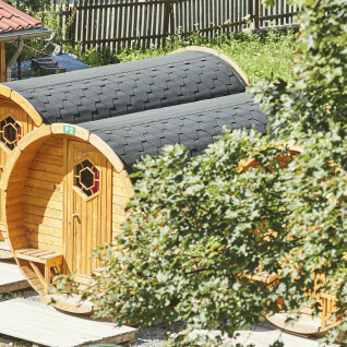 Chalets en bois en forme de tonneau au Camping Dreiländereck - Lodge & Wijnvat Tirol, entourés de verdure.
