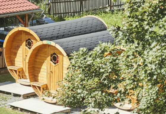 Træhytter formet som vintønder på Camping Dreiländereck - Lodge & Wijnvat Tirol, omgivet af natur.