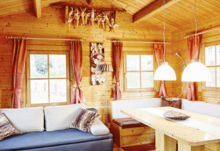 Knus houten lodge-interieur met zithoek en eettafel bij Camping Dreiländereck - Lodge & Wijnvat Tirol.