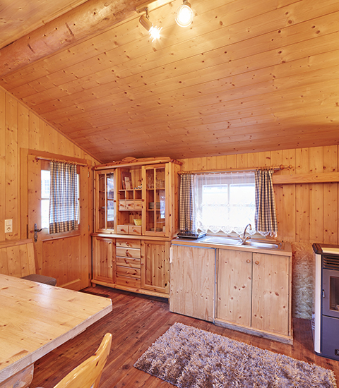Vista interior de la cabaña glamping revestida de madera en Camping Dreilandereck - Lodge & Wijnvat Tirol, ambiente acogedor.