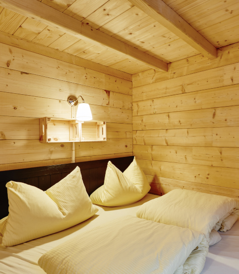 Cozy wooden bedroom inside glamping at Camping Dreiländereck - Lodge & Wijnvat Tirol with soft lighting.