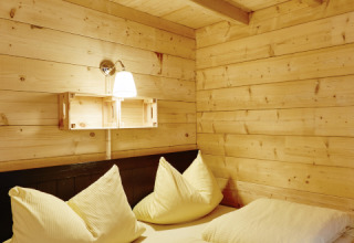 Camera da letto in legno nella glamping Camping Dreiländereck - Lodge & Wijnvat Tirol, atmosfera accogliente.