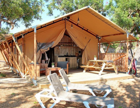 Glamping accommodation at Park Mas Patoxas – Bungalows Costa Brava with a deck, wood furniture, and lounge chairs.