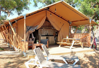 Glampingverblijf bij Park Mas Patoxas – Bungalows Costa Brava met houten terras, zitruimte en ligstoelen.