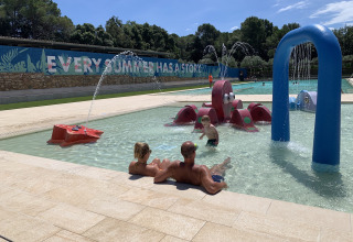 Familie entspannt am Kinderpool mit Wasserattraktionen im Park Mas Patoxas – Bungalows Costa Brava.