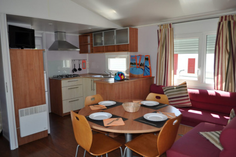 Interno dell'alloggio glamping Park Mas Patoxas con cucina, tavolo da pranzo e divano, Costa Brava.