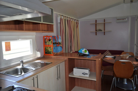 Vue intérieure d’un hébergement glamping moderne au Park Mas Patoxas – Bungalows Costa Brava avec cuisine équipée.