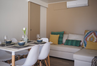 Sala de estar moderna en Park Mas Patoxas – Bungalows Costa Brava con mesa de comedor y sofá blanco.