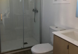 Salle de bain moderne au Park Mas Patoxas – Bungalows Costa Brava, avec douche, toilettes et lavabo.