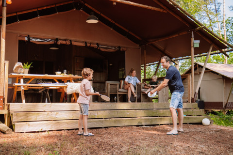 Familie beim Spielen vor einer Glamping-Lodge auf Camping Samoza – Glamping Lodges Veluwe im Grünen.