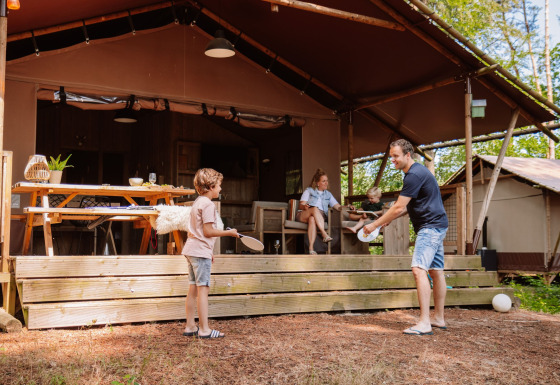 Familie nyder en ferie foran en glamping-lodge på Camping Samoza – Glamping Lodges Veluwe i naturen.