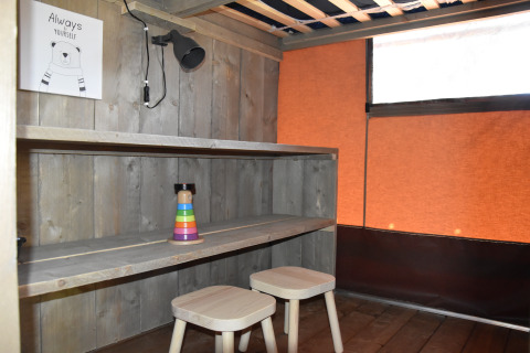 Innenbereich einer Glamping-Lodge bei Camping Samoza – Glamping Lodges Veluwe mit Holzregal und Hockern.