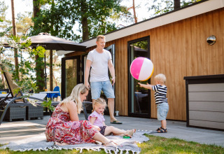 Familia disfruta y juega con una pelota afuera de una cabaña en Camping Samoza – Glamping Lodges Veluwe.