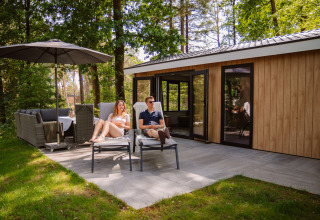 Couple relaxes on loungers outside their glamping lodge at Camping Samoza – Glamping Lodges Veluwe.
