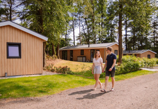Pareja paseando frente a cabañas glamping modernas en Camping Samoza – Glamping Lodges Veluwe, naturaleza.