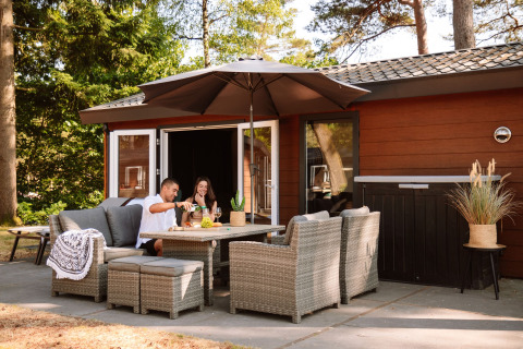 Terrazza esterna di Camping Samoza – Glamping Lodges Veluwe con coppia che si gode cibo e bevande insieme.