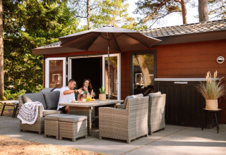 Udendørs terrasse ved Camping Samoza Glamping Lodges Veluwe med par, der nyder mad og drikke i solen.