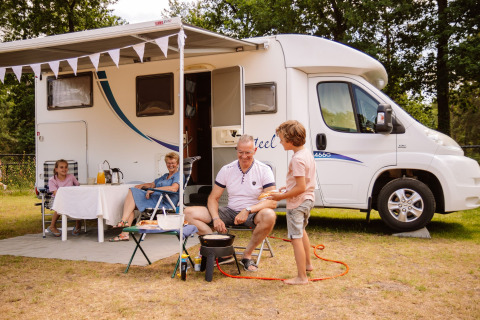 Famille prenant un repas devant un camping-car à Camping Samoza – Glamping Lodges Veluwe, Pays-Bas.