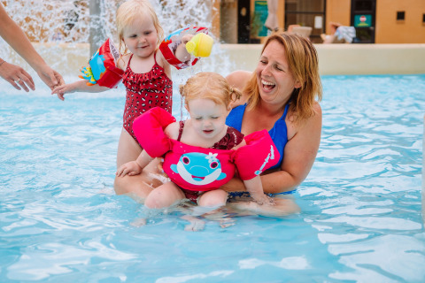 Mother and two young children enjoy the swimming pool with floaties at Camping Samoza – Glamping Lodges Veluwe.