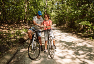 Two adult cyclists pause in a forest to check a map, glamping experience near Camping Samoza, Veluwe.