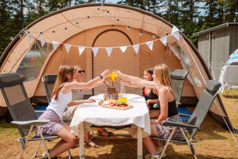 Cuatro mujeres disfrutan de glamping frente a una gran tienda en Camping Samoza – Glamping Lodges Veluwe.