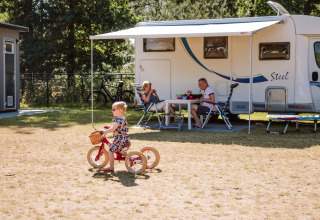Gezin geniet buiten de caravan bij Camping Samoza – Glamping Lodges Veluwe, kind op driewieler.