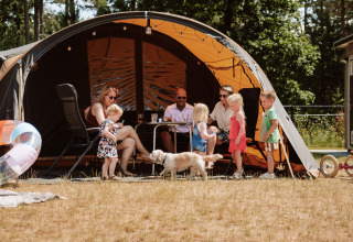 Familia disfrutando del glamping en Camping Samoza – Glamping Lodges Veluwe con niños y perro al sol.